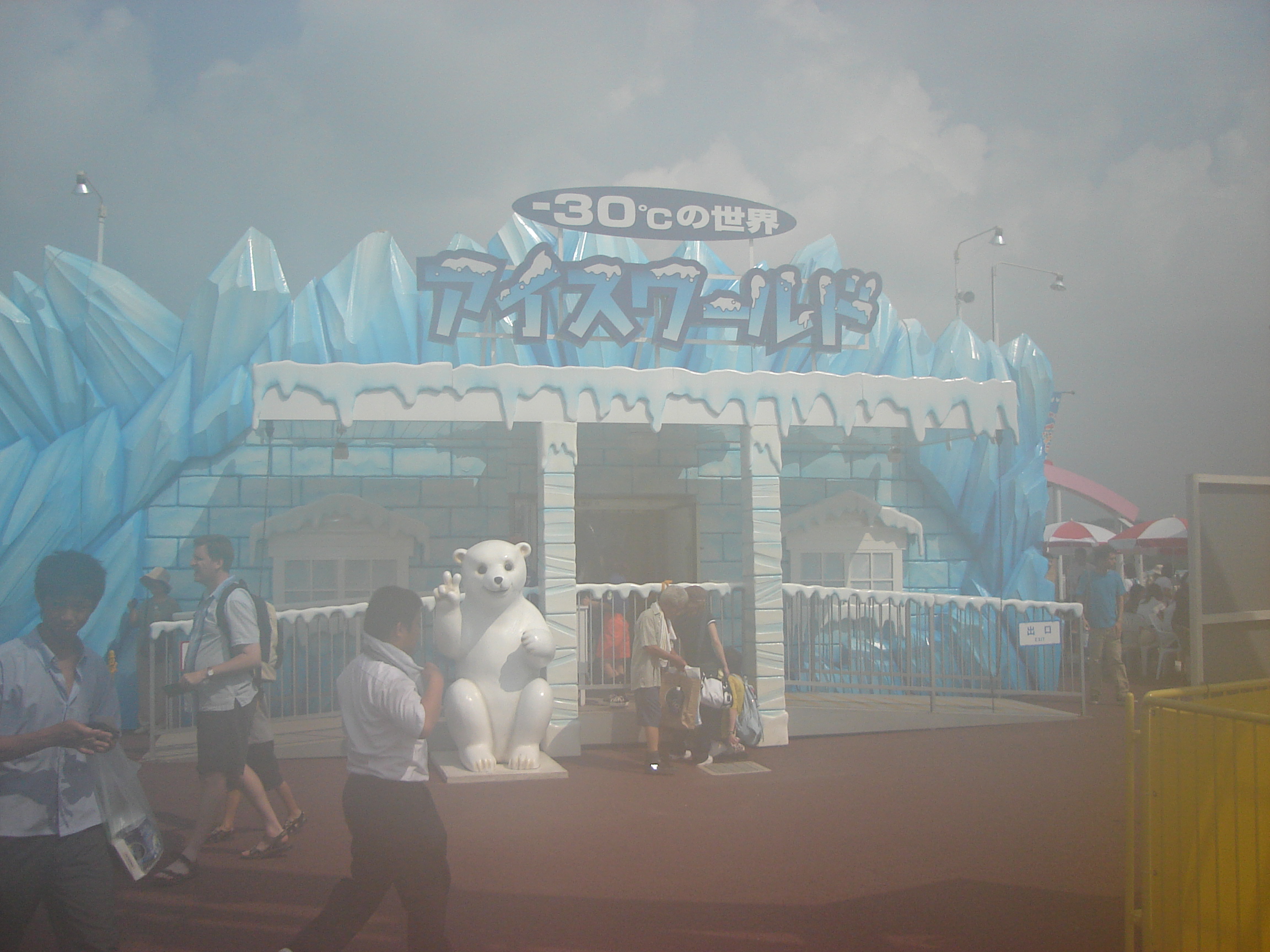 a foggy photo of a building decorated like an iceburg with a polar bear statue in front.