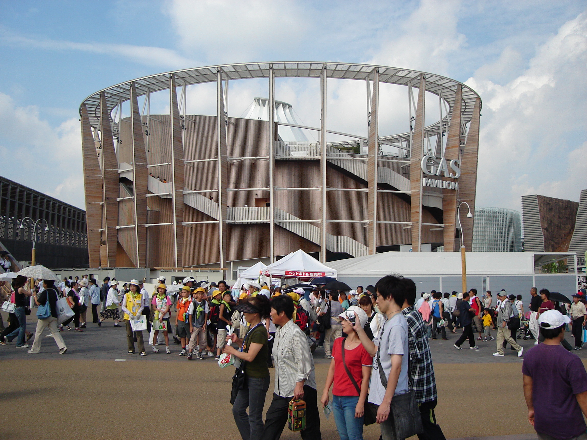 crowds wander near a round wooden building