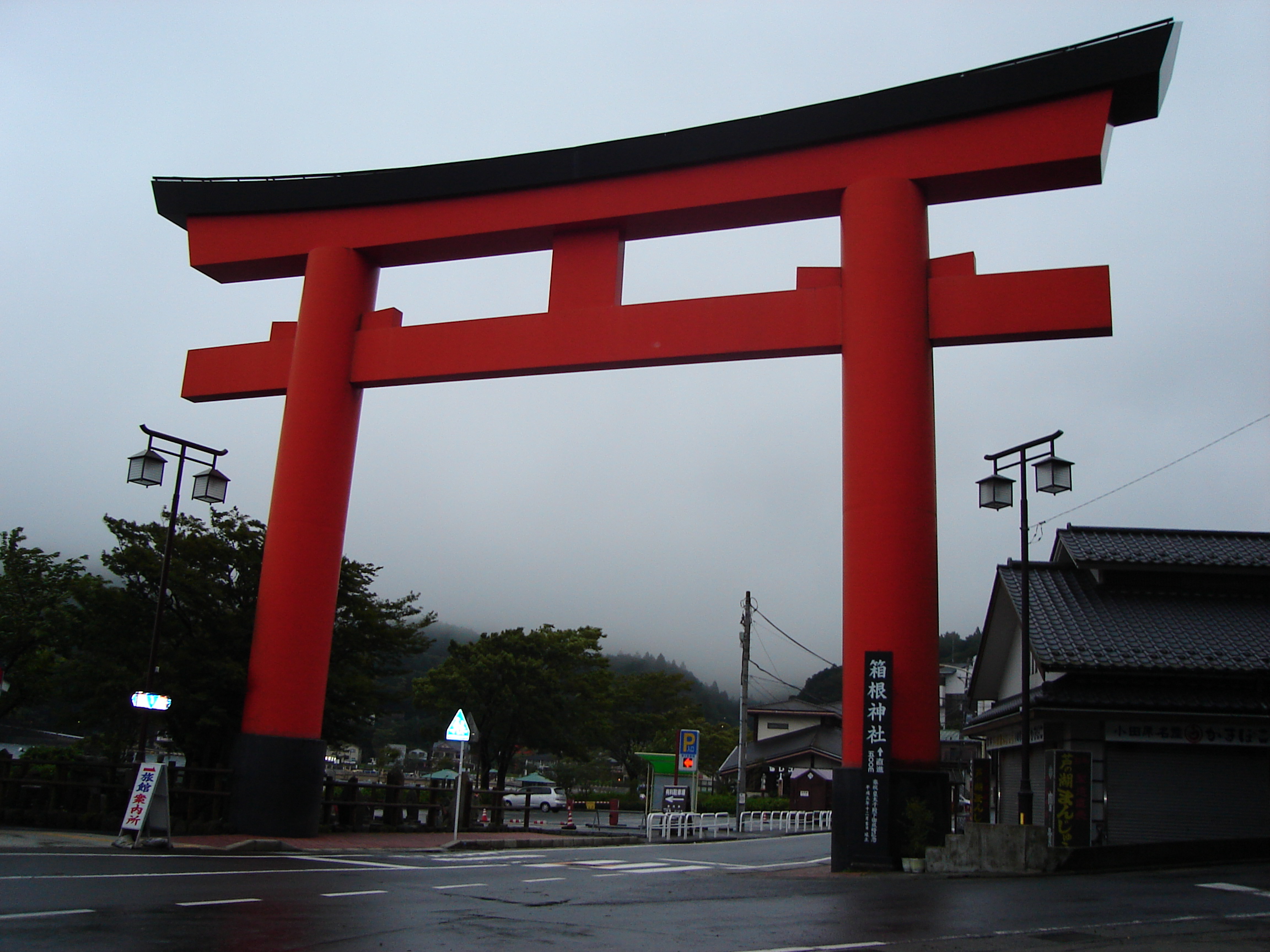 a large vermillion torii gate spans a city street