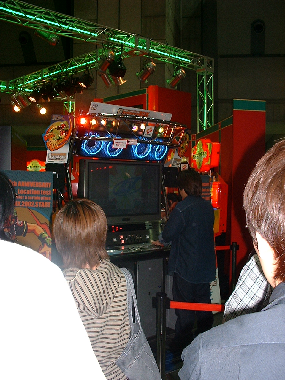 a small crowd watches someone play a rhythm game