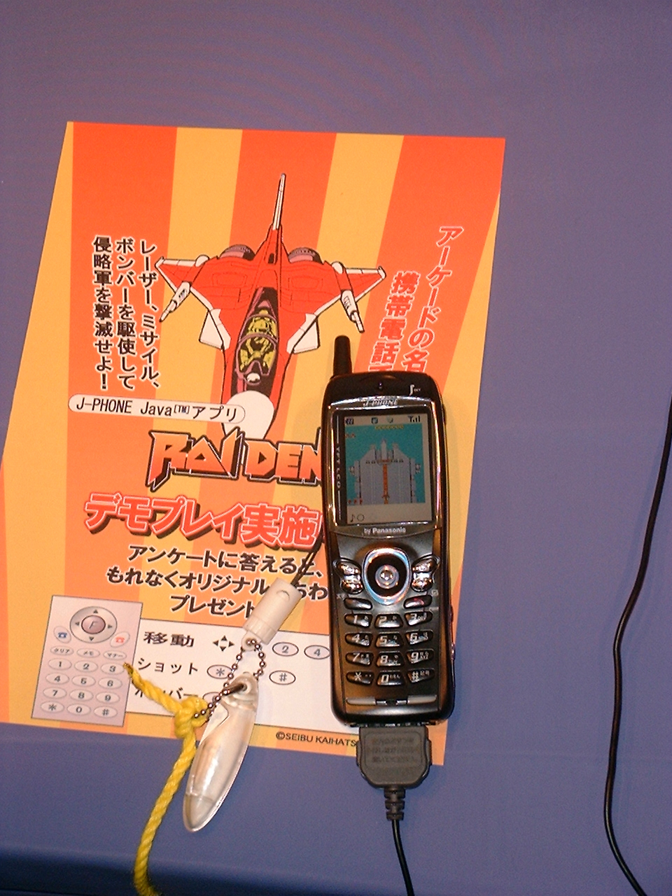 a mobile phone on a counter near an image of a plane with the raiden logo