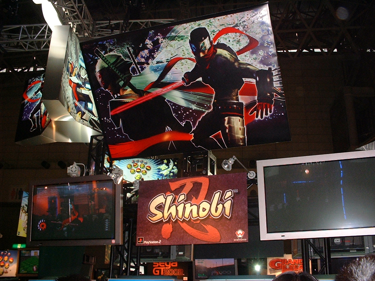 a giant poster of a ninja and the logo for shinobi with video screens