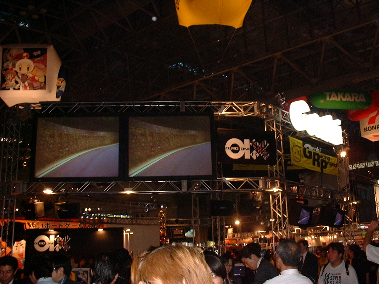 a crowd of people around the Genki booth showing a racing game