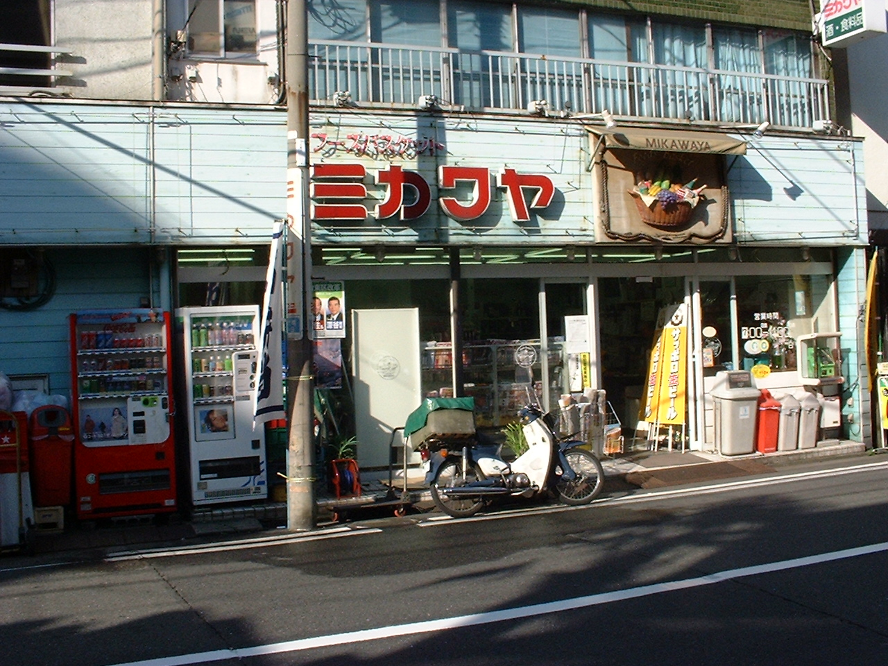 a pale green building with large red japanese letters above the door