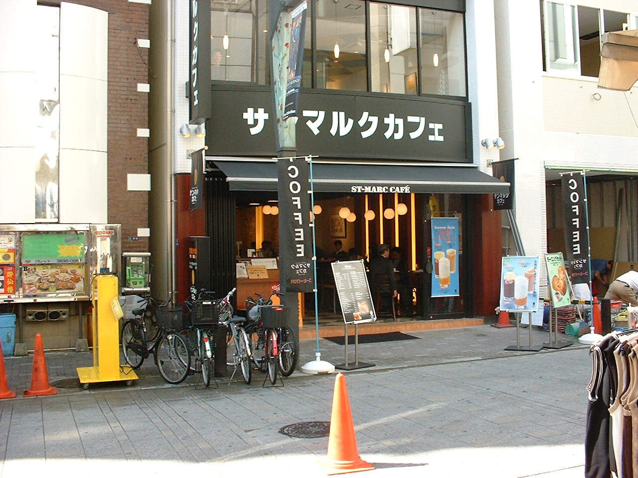 the exterior of a small cafe with flags outside that read coffee in english
