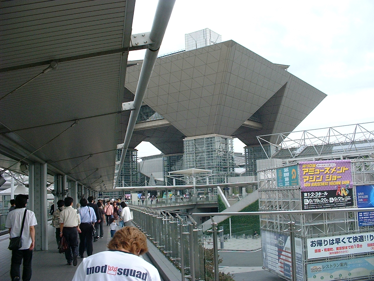 people on a walkway to a building with inverted triangular structures