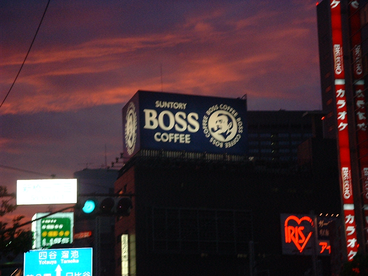 an illuminated sign for suntory boss coffee at dusk