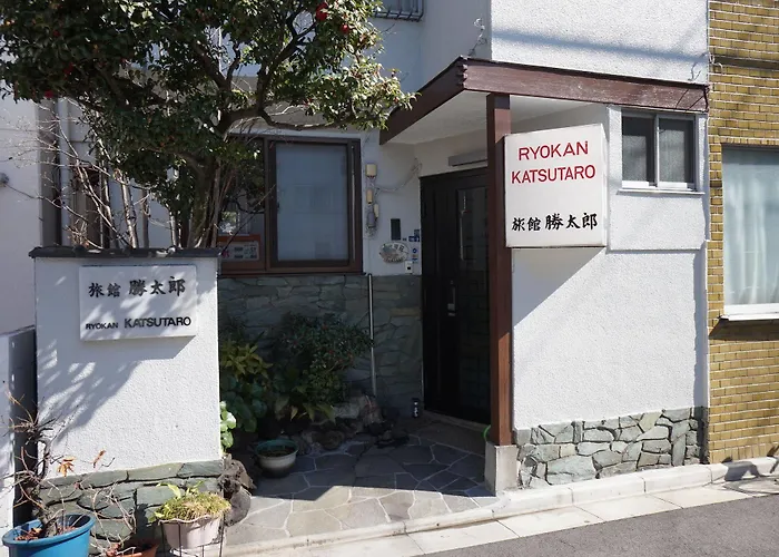 a small building entrance with a tree.  a small sign reads ryokan katsutaro