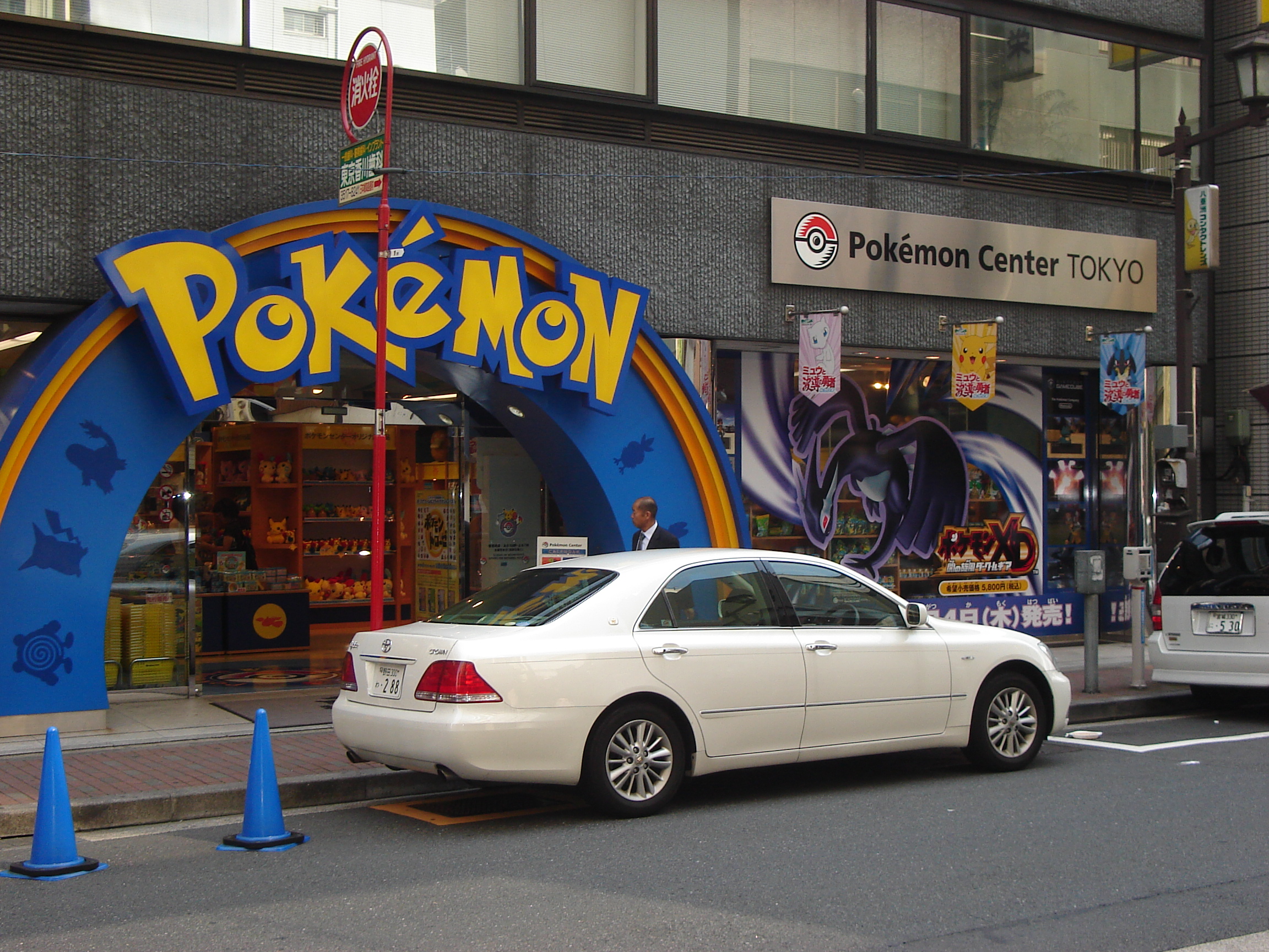 a curved blue entryway with a large pokémon logo on a grey building