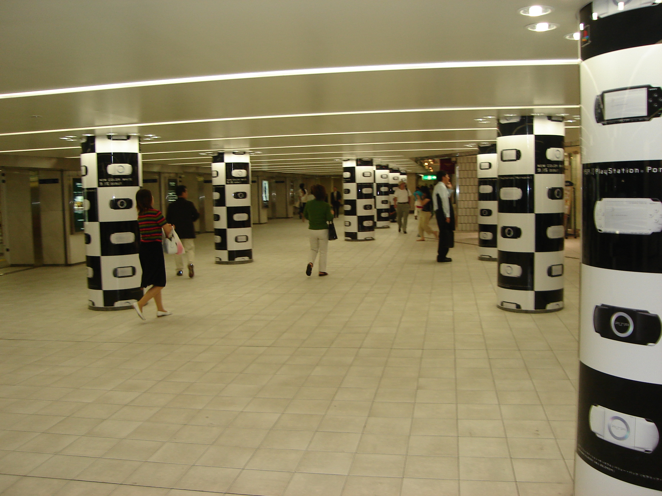 pillars in a subway station are wrapped in repeating images of the playstation portable