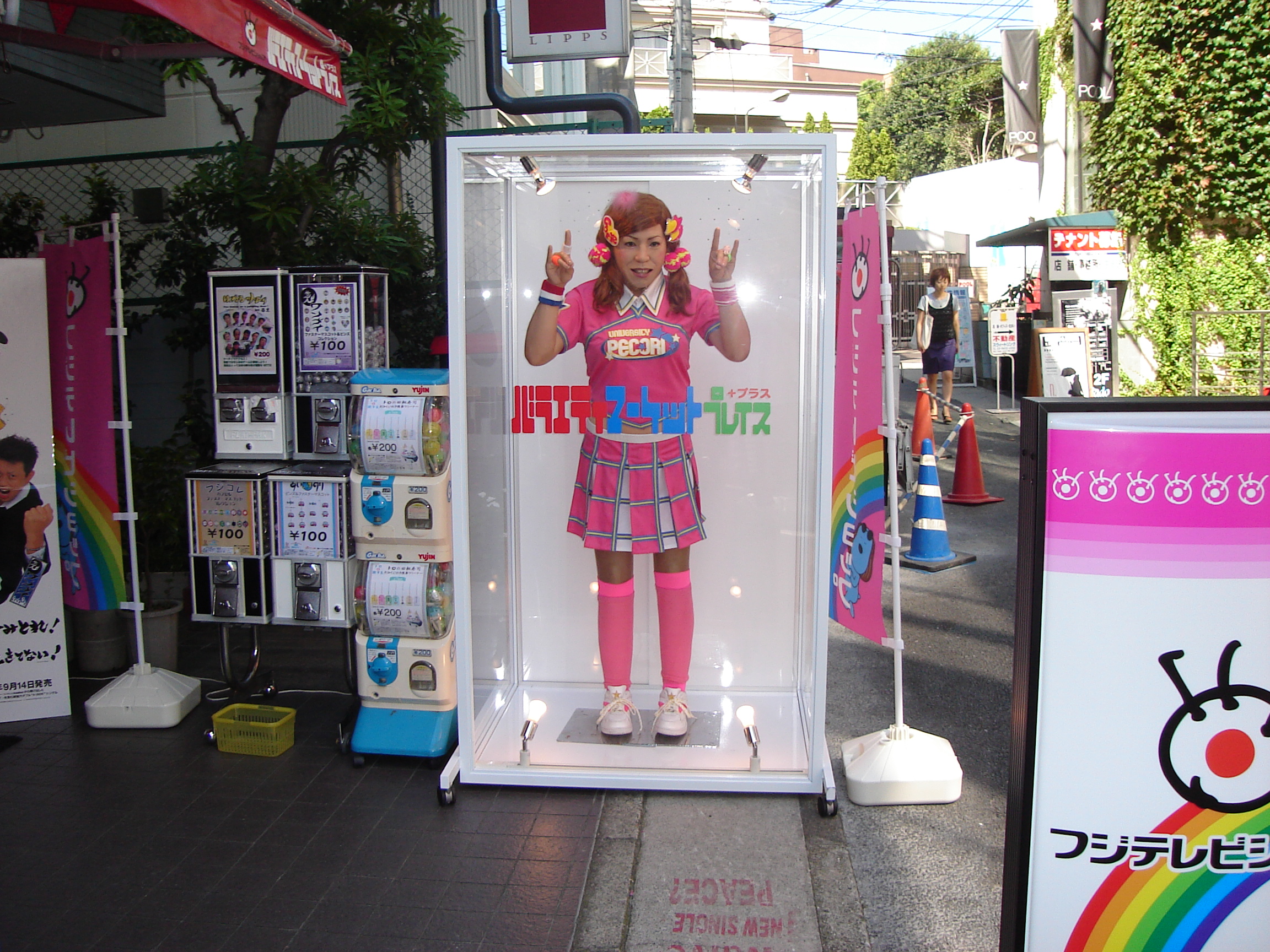 a mannequin dressed in mostly pink makes a metal horns gesture in a clear case outside a store
