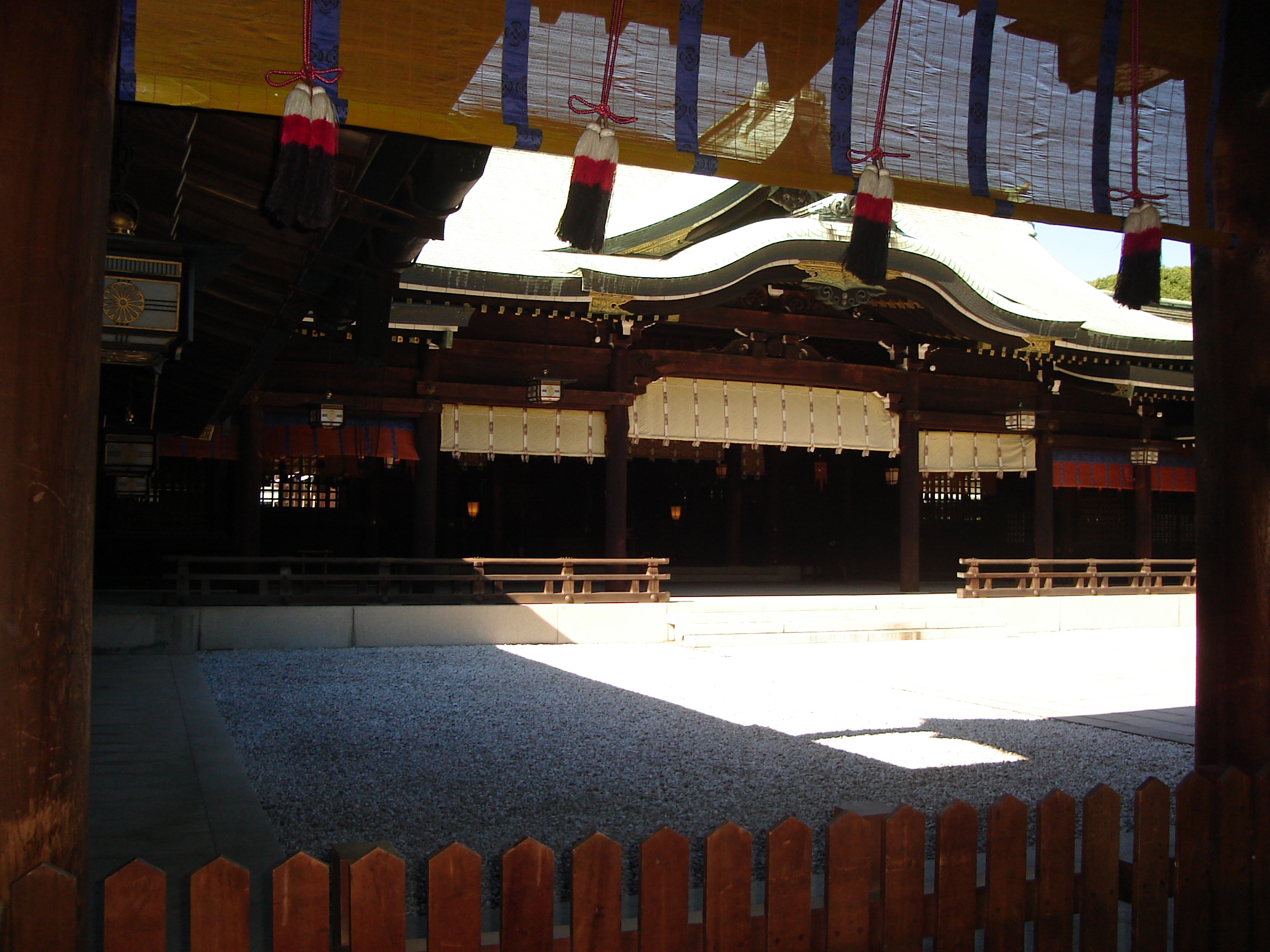 a closer view of the dark shrine building where lanterns and curtains are barely visible
