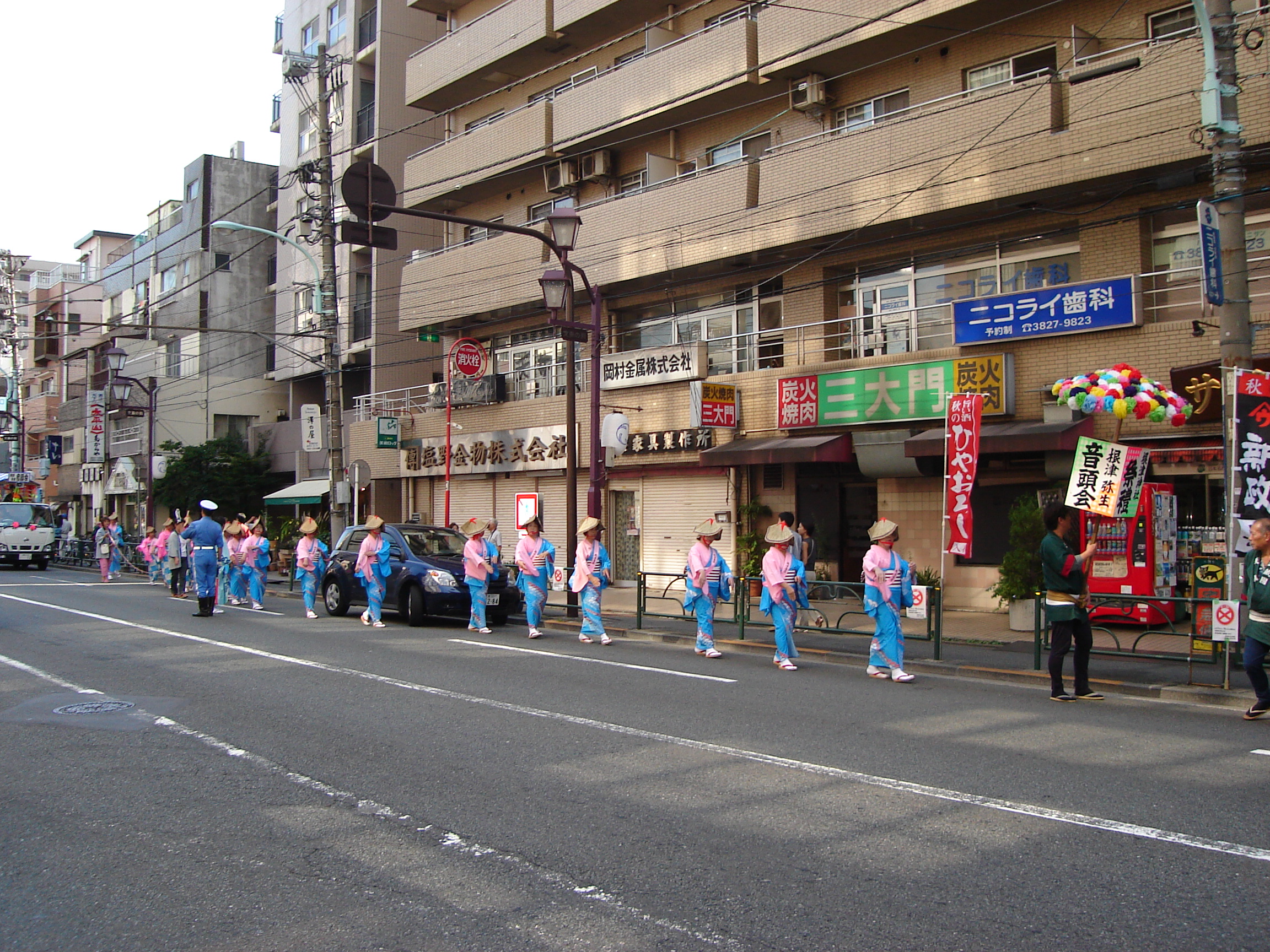 a procession of people dressed in blue and pink along a street