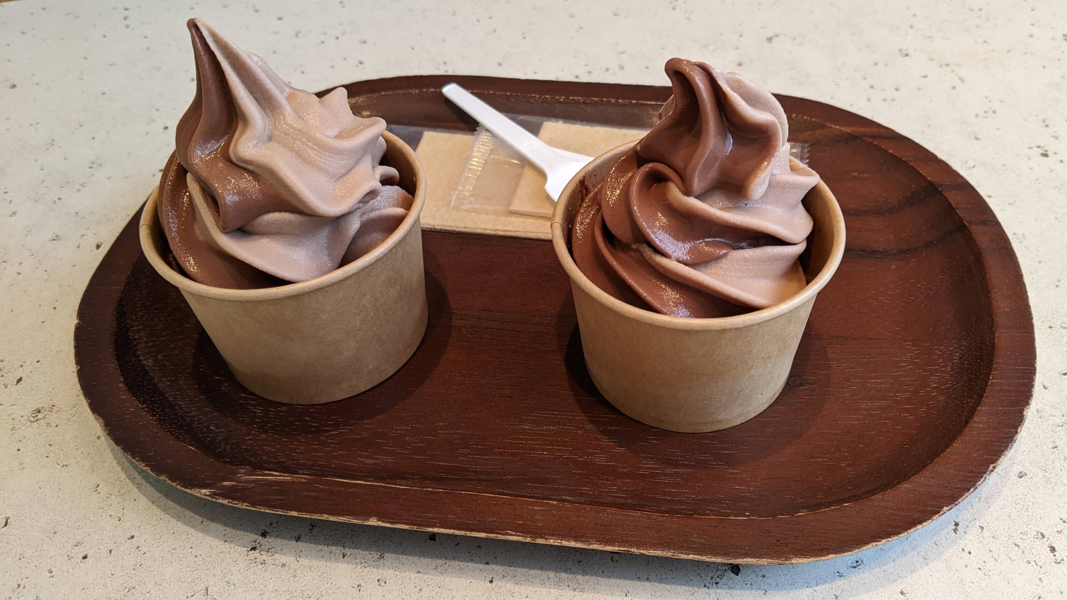 Cups of chocolate ice cream on a wooden tray