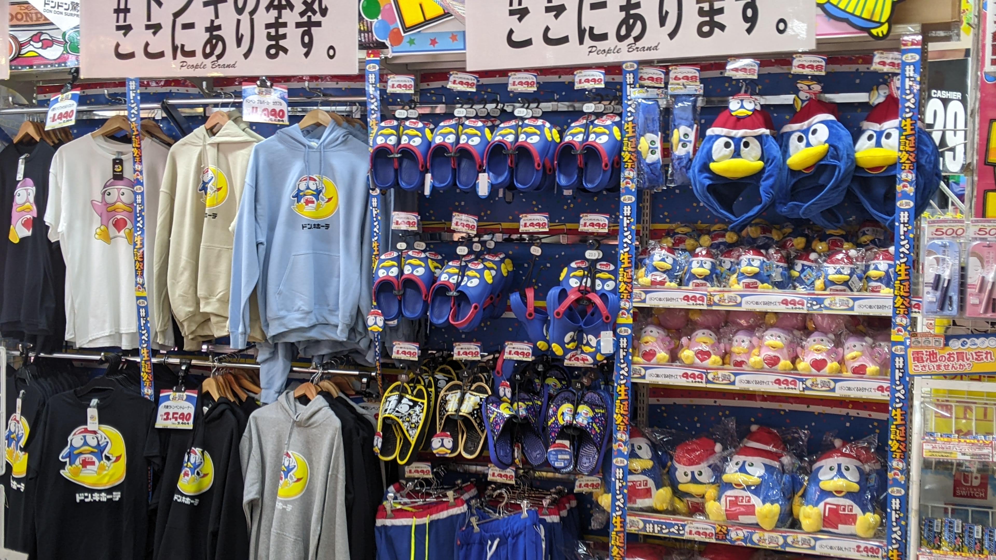 A display of penguin mascot shirts, slippers, and stuffed animals, etc.