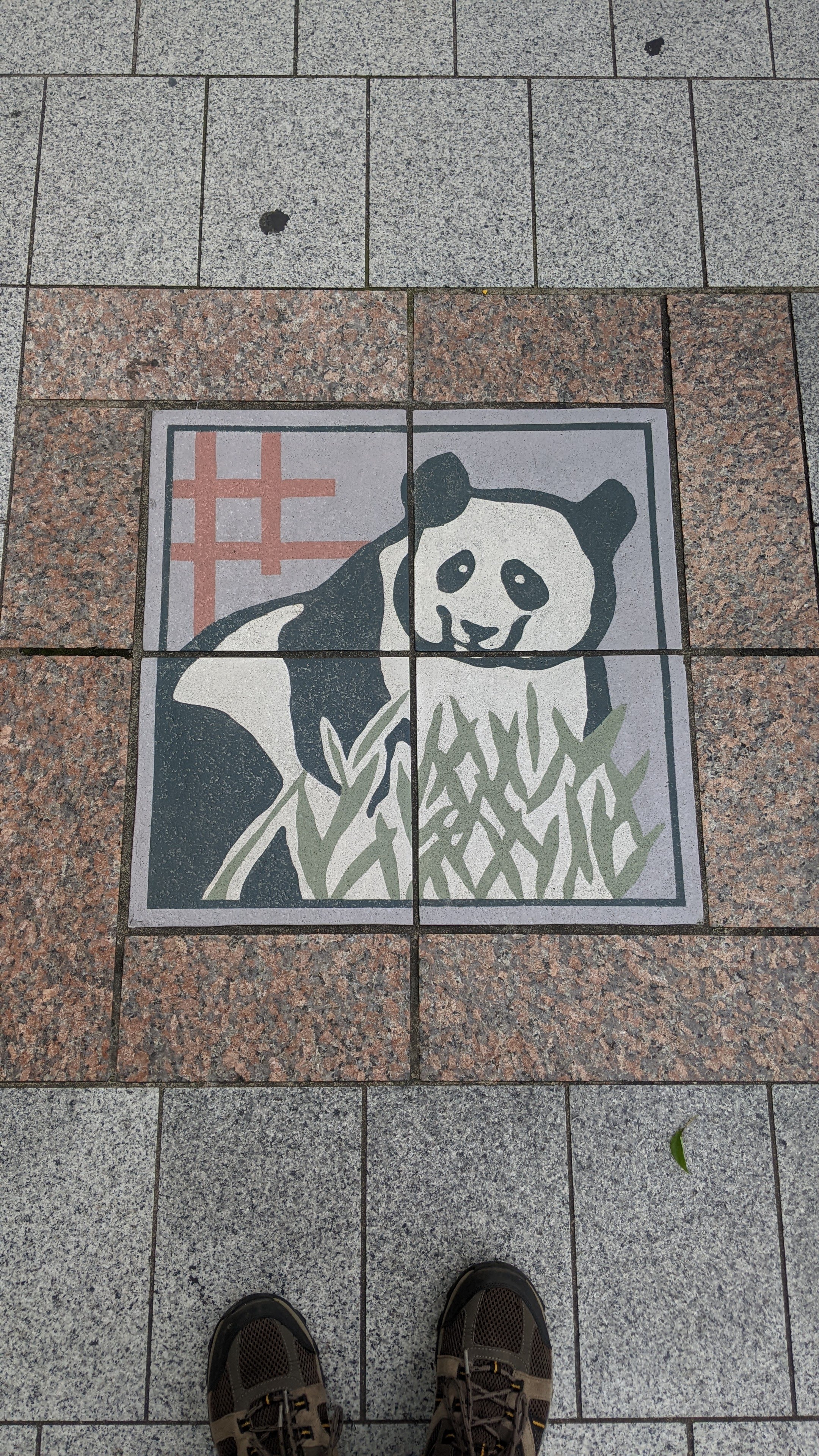 An image of a panda made up of four tiles on the sidewalk