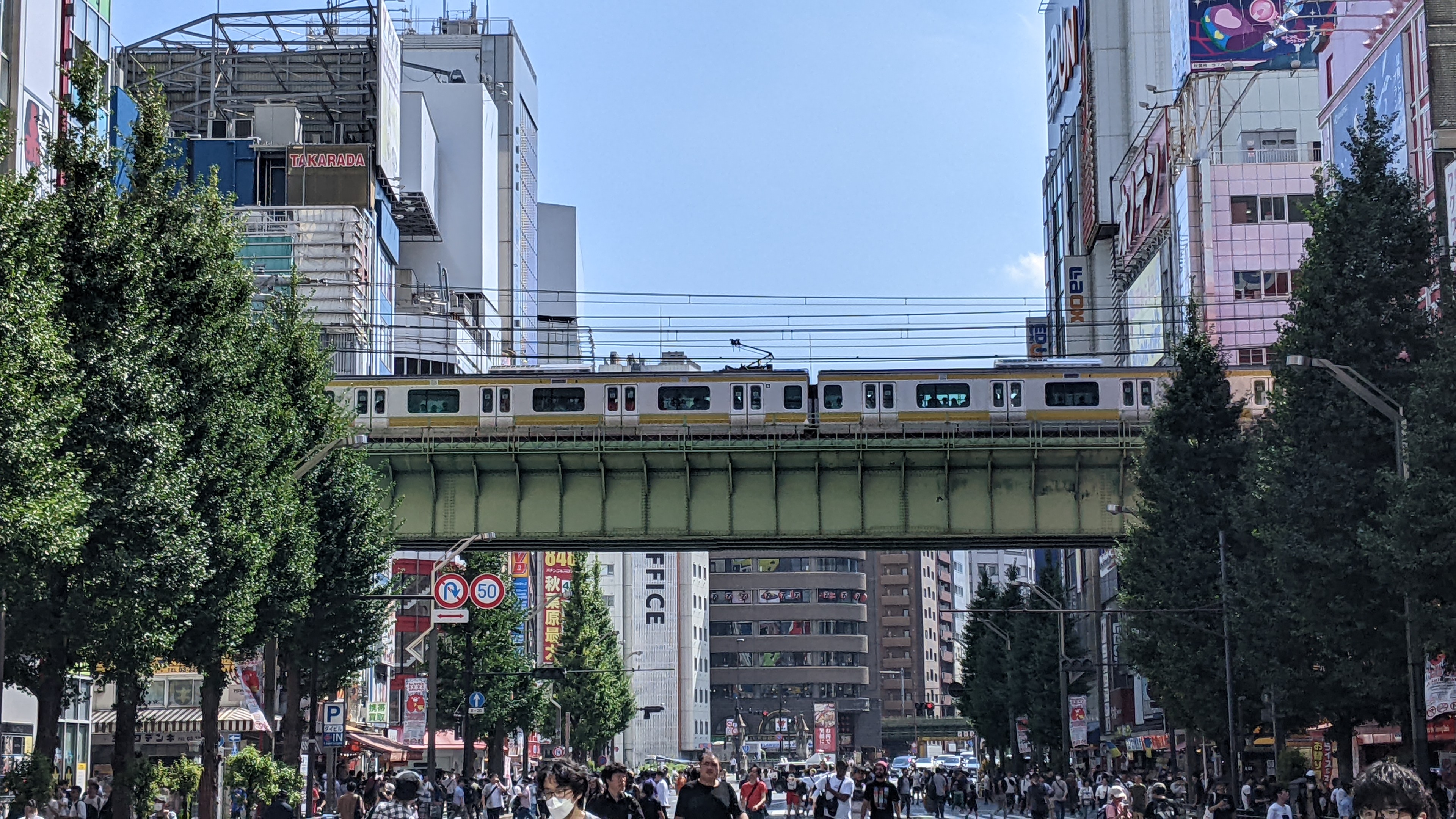 A train passing over the pedestrian-filled main street