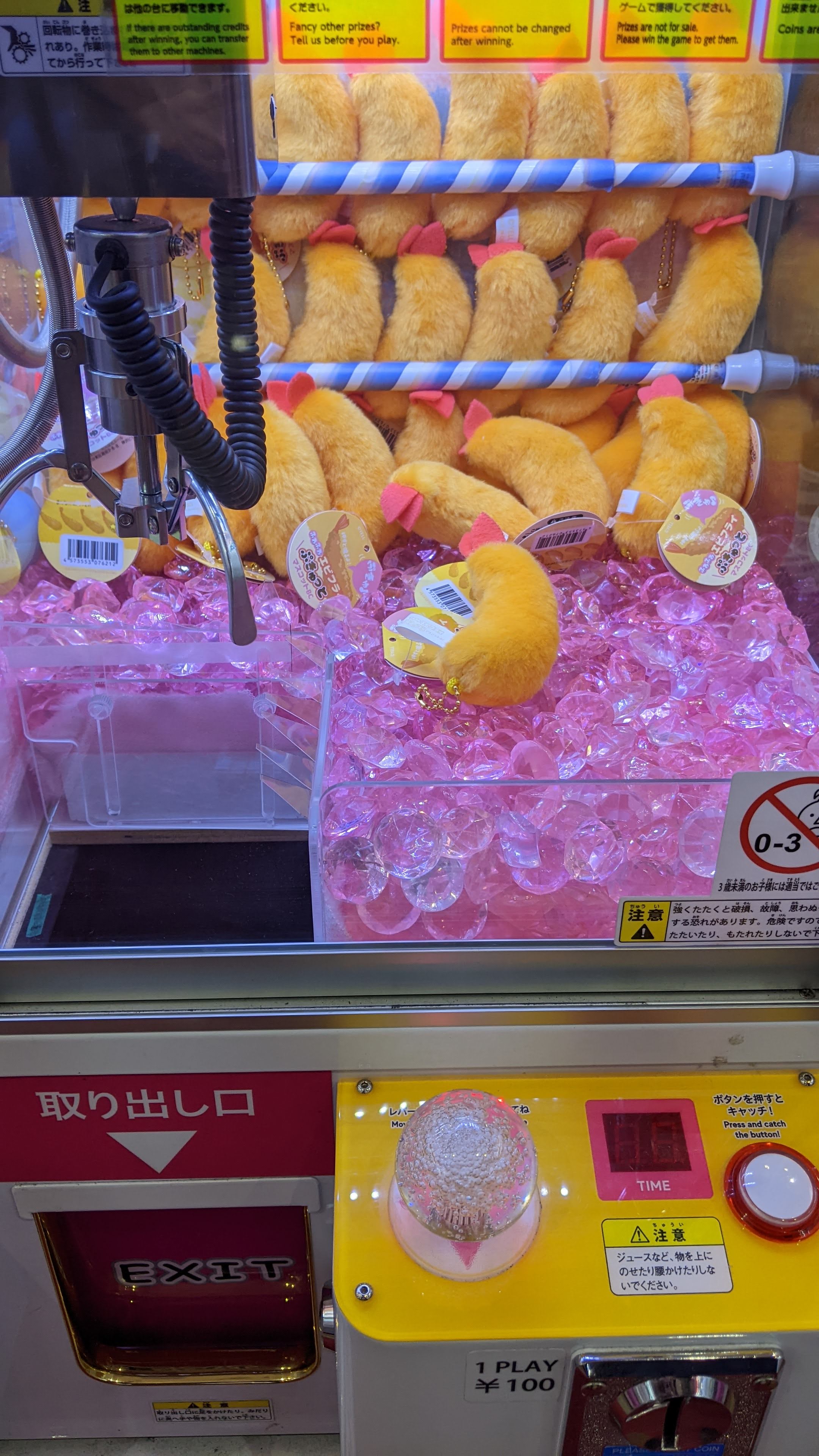 A crane game with mini plush tempura shrimp inside