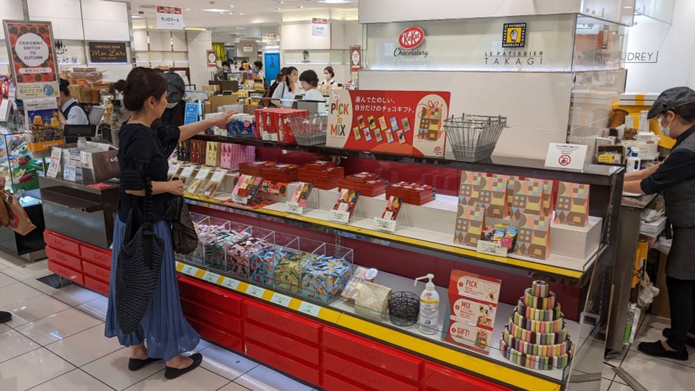 A woman shops at the Kit Kat Chocolatory counter with a display of boxes and items in bins