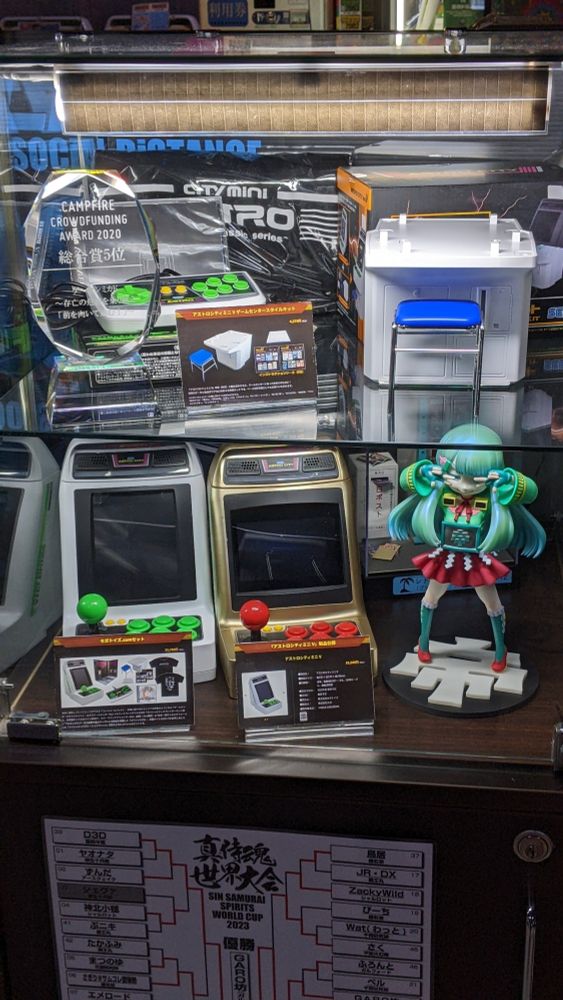 Display case of mini arcade machines and a figure of the arcade's mascot girl