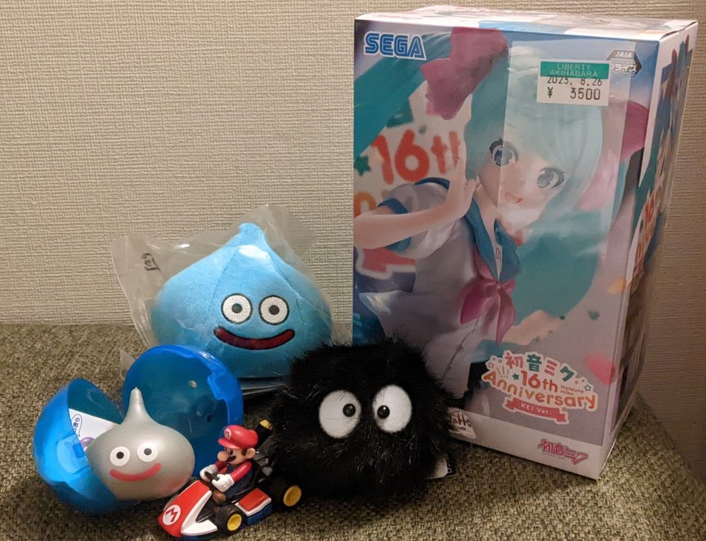 2 dragon quest slimes, a mario kart toy, a dust sprite and a Hatsune Miku figure in the box